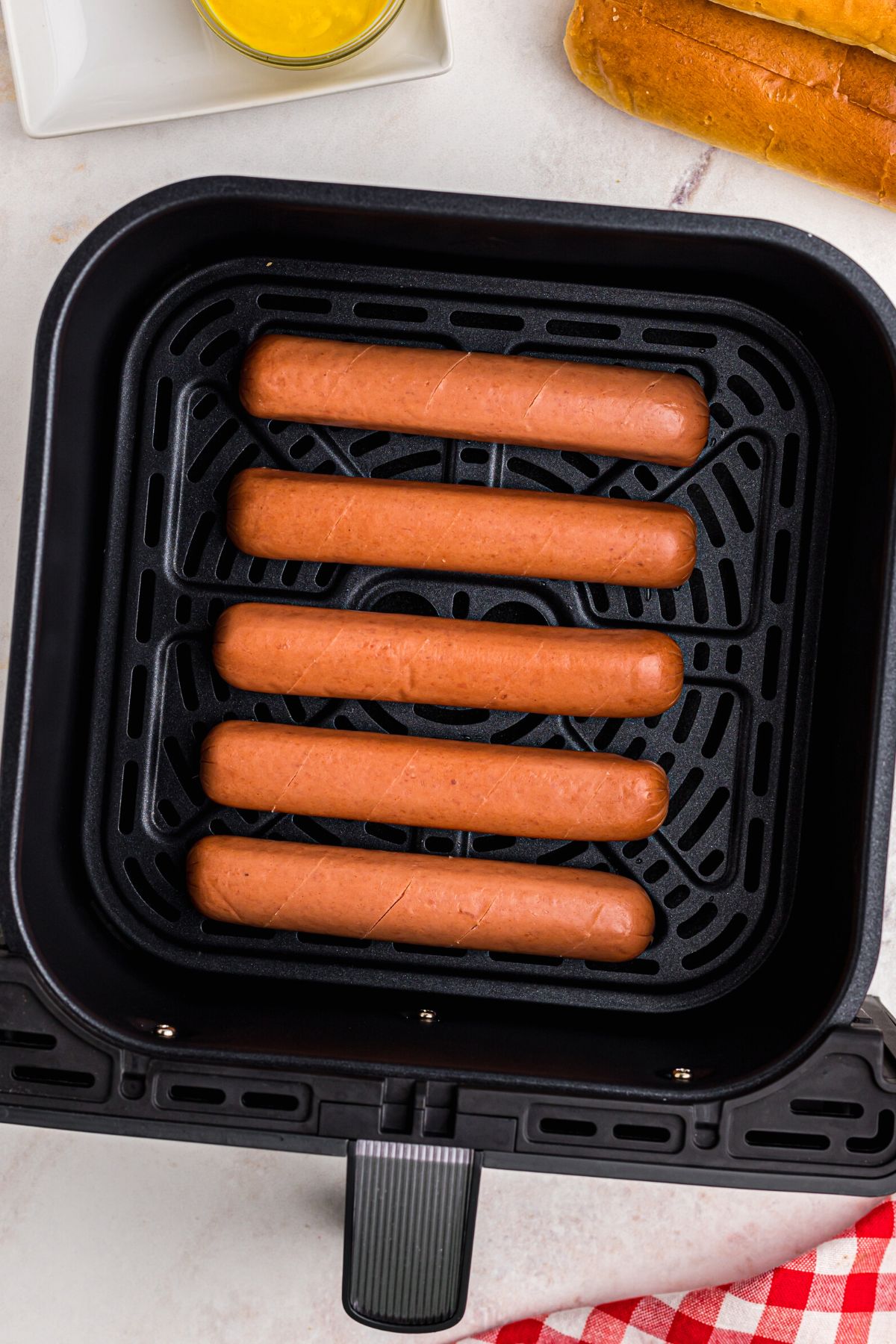 Hot dogs with slits cut into them placed in the air fryer basket before cooking