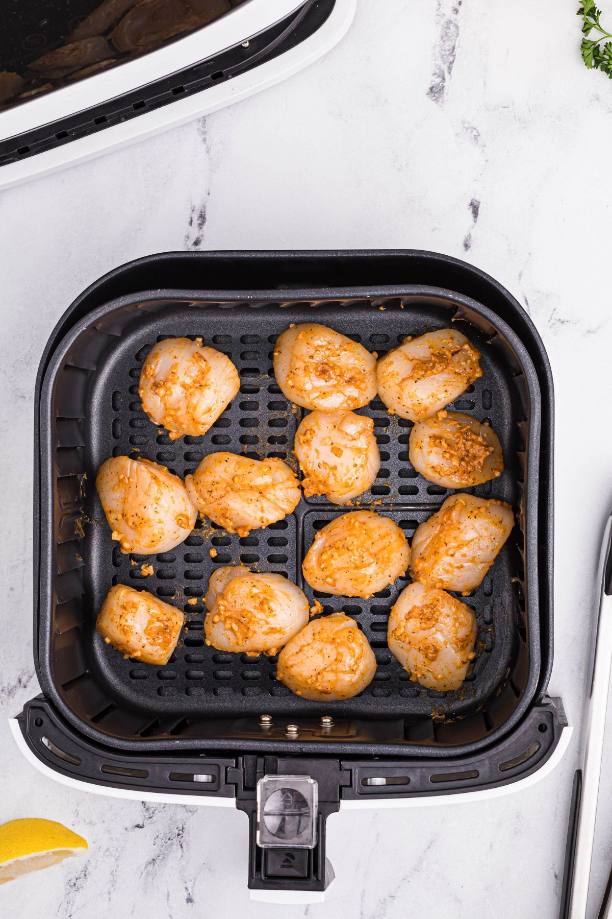 Uncooked seasoned sea scallops in an air fryer basket before being cooked. 