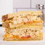 Air fryer tuna melt served on golden Texas toast with tomatoes and melted cheese cut in half and served on a round white plate,