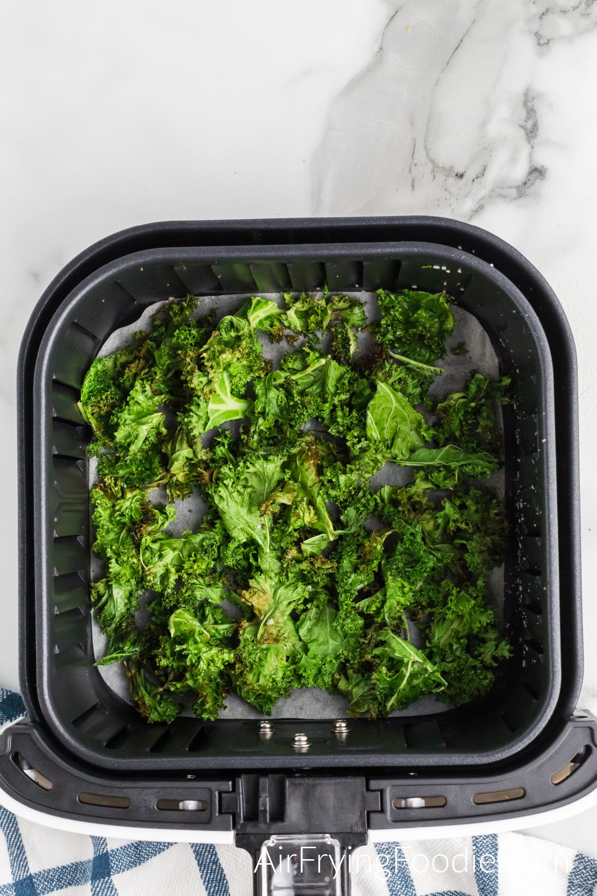 A picture of the kale fully cooked in the air fryer basket.