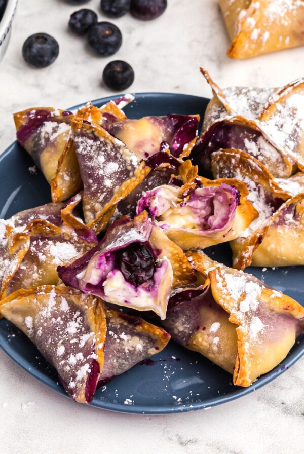 Crispy golden wontons filled with blueberry cheesecake filling on a blue plate.