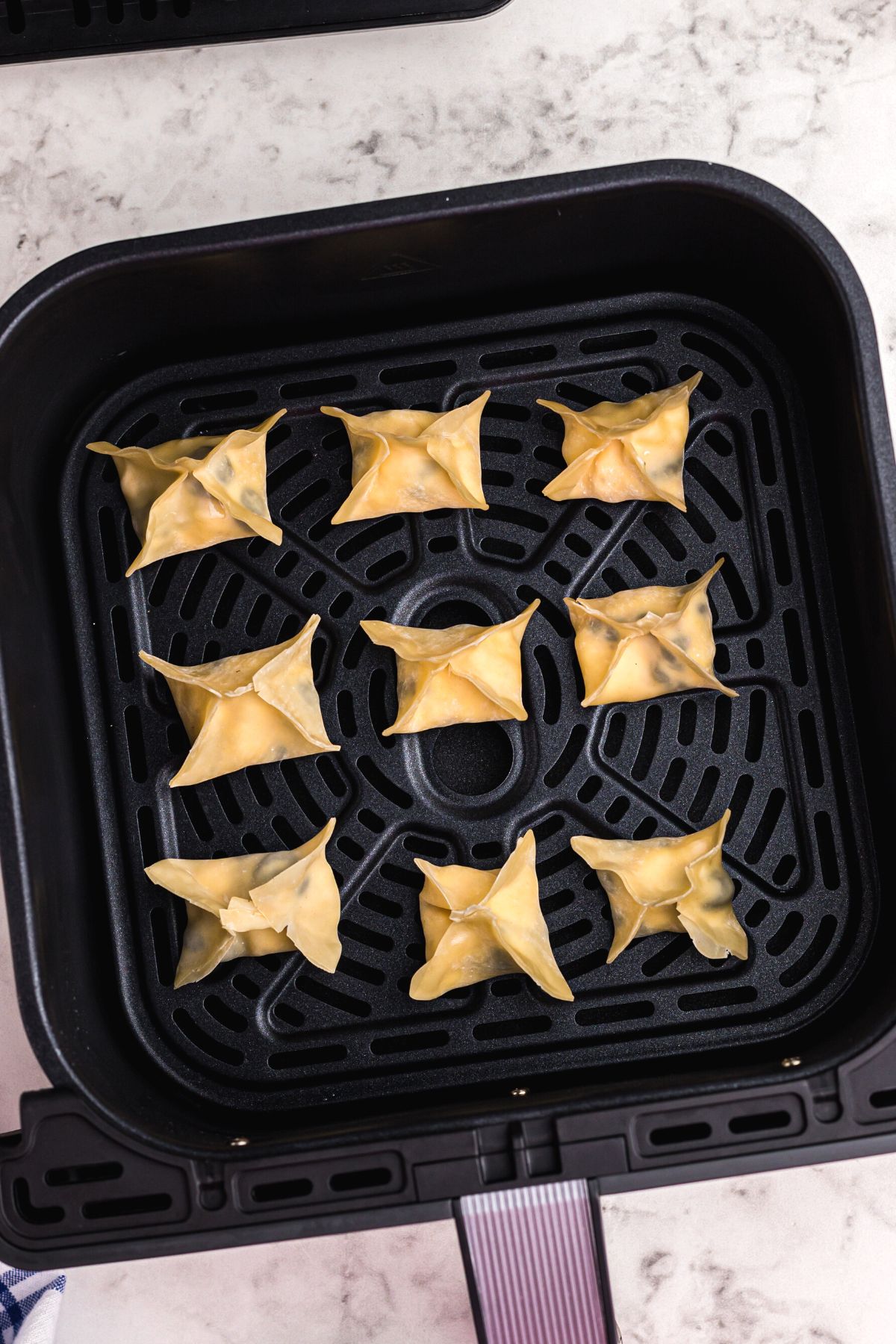 Wontons in the air fryer basket before being cooked