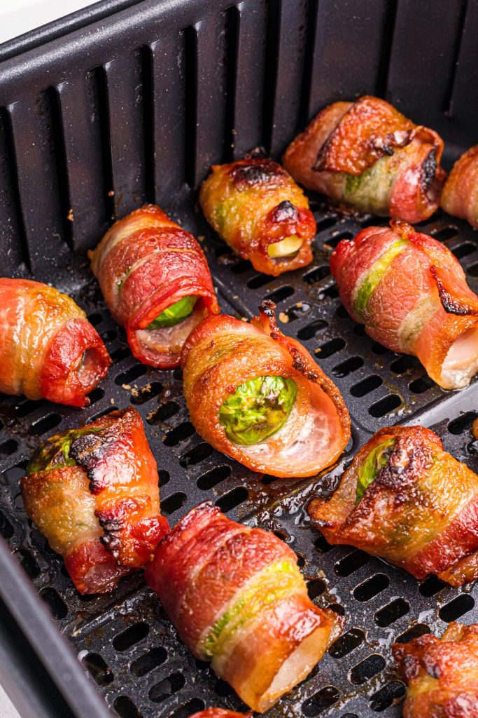 Juicy crispy bacon wrapped around brussels sprouts in the air fryer basket after being cooked