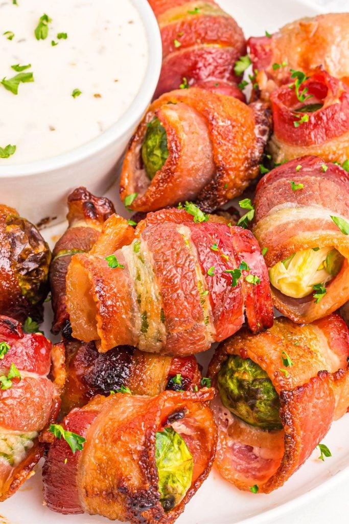 Crispy golden bacon wrapped around brussels sprouts on a white plate