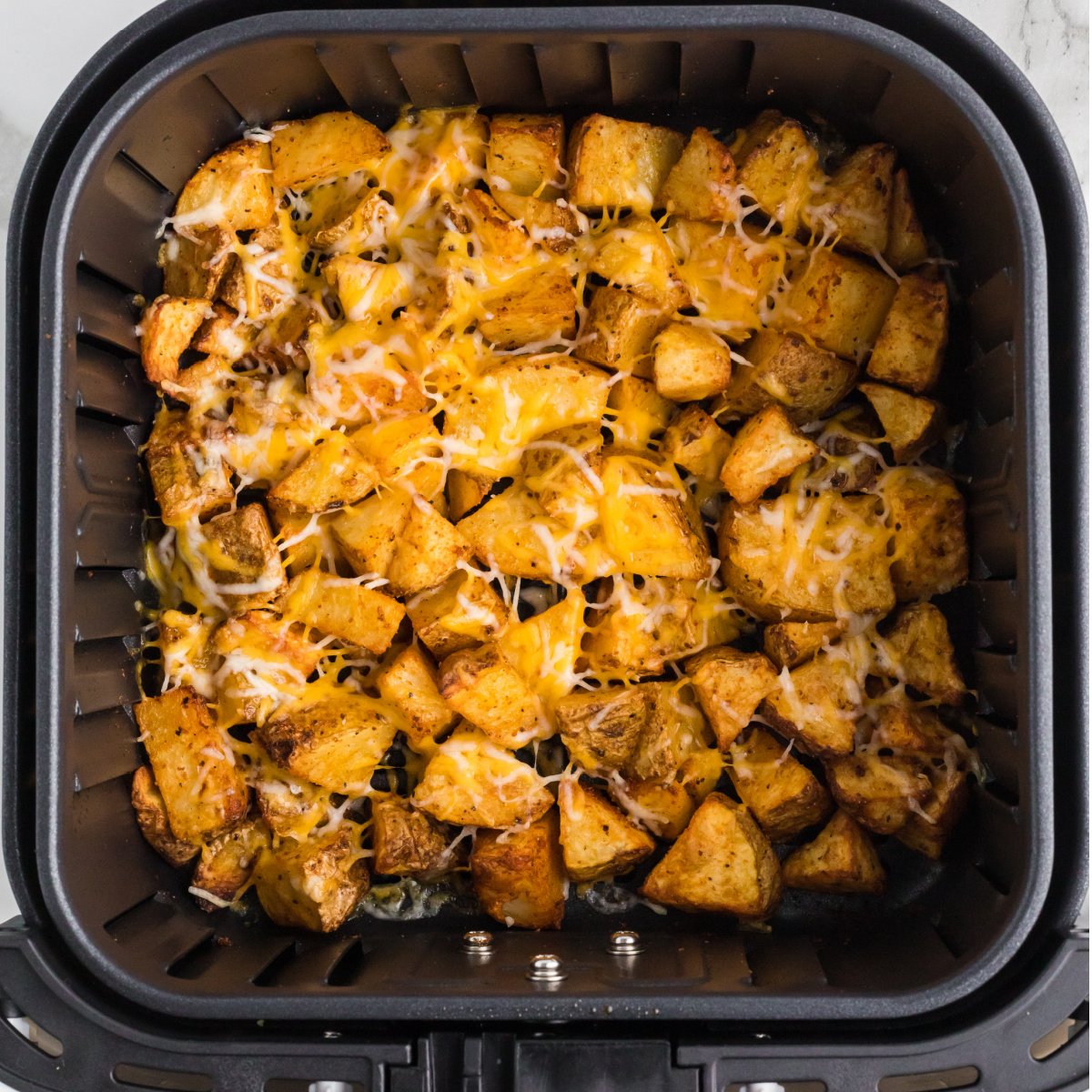 Cheesy potatoes in the basket of the air fryer.