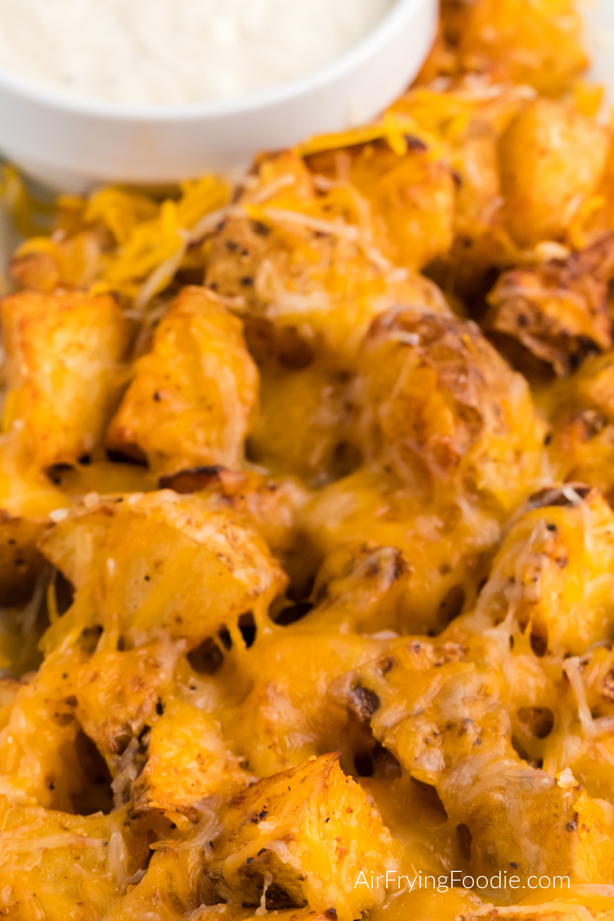 Close up photo of cheesy potatoes made in the air fryer and served with ranch dipping sauce.