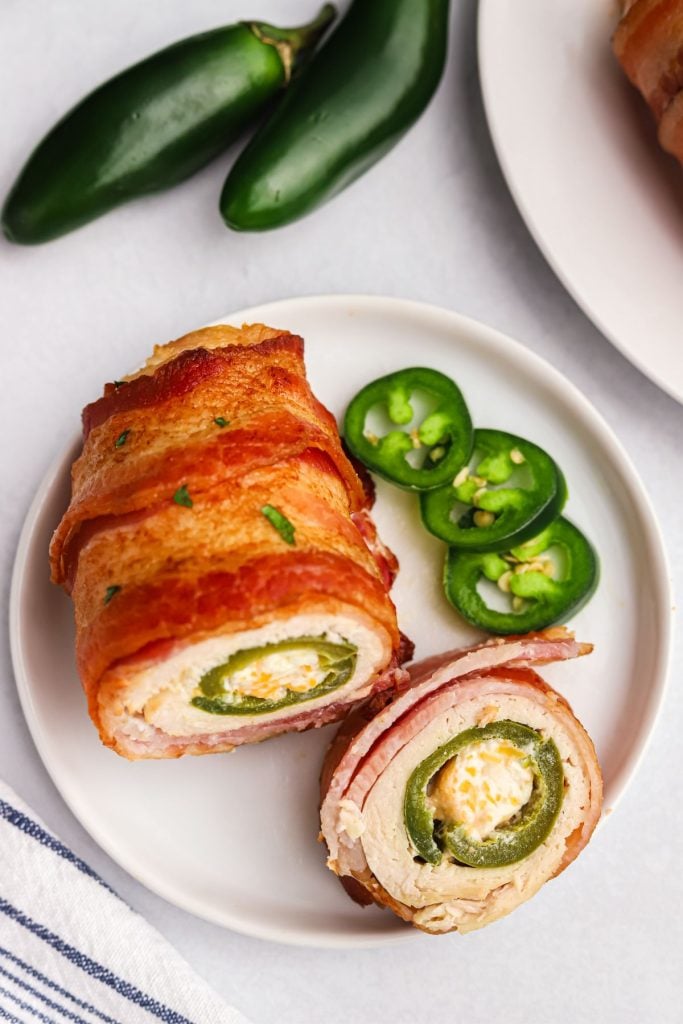 Bacon wrapped chicken around a jalapeno popper, cut open and on a white small plate