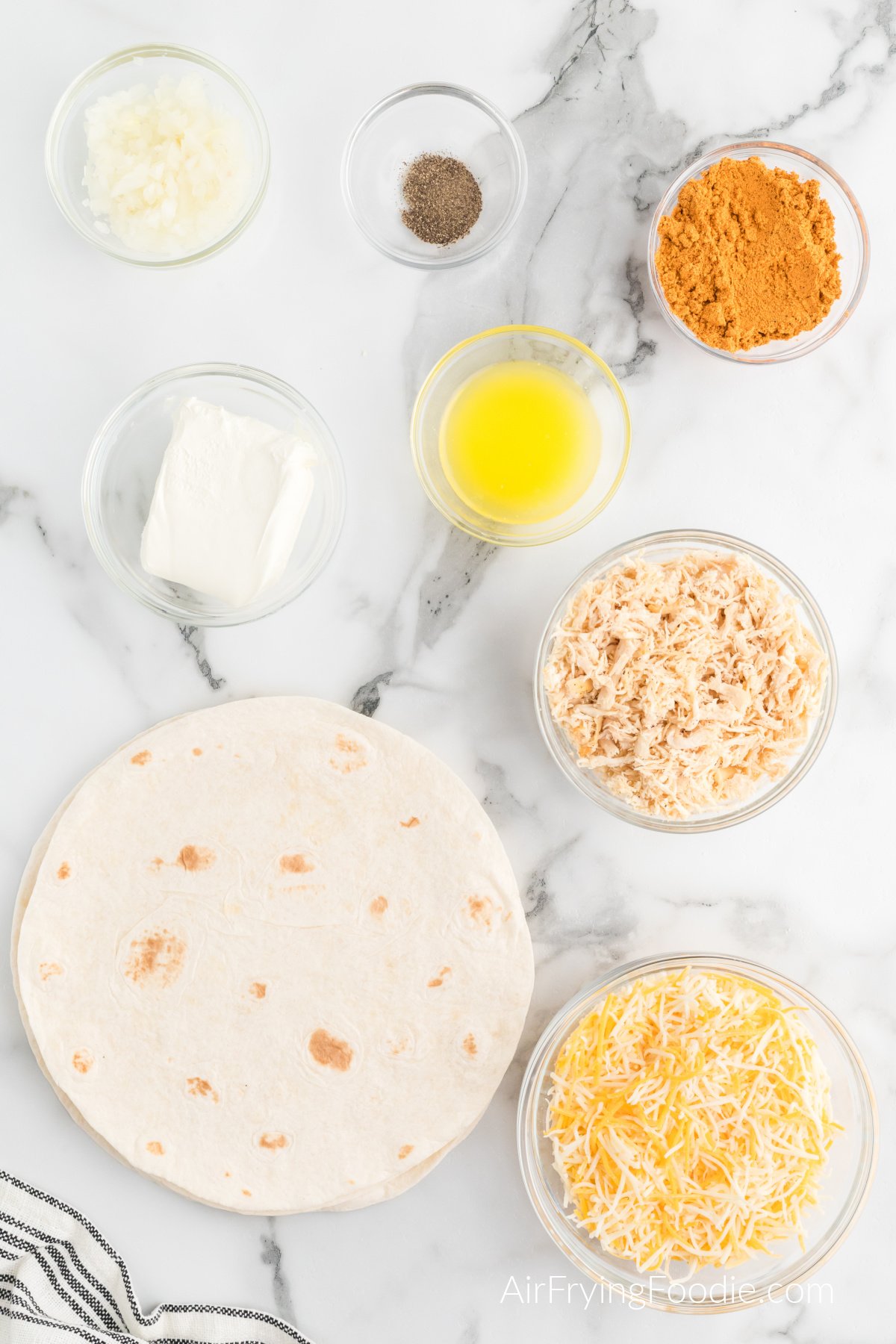 Ingredients needed to make chimichangas in bowls in a marbnle table top.