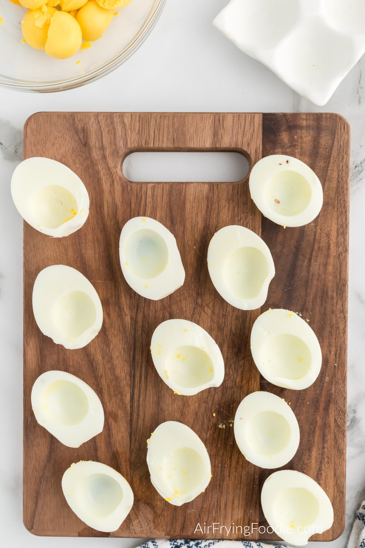 Boiled eggs sliced lengthwise on a cutting board.