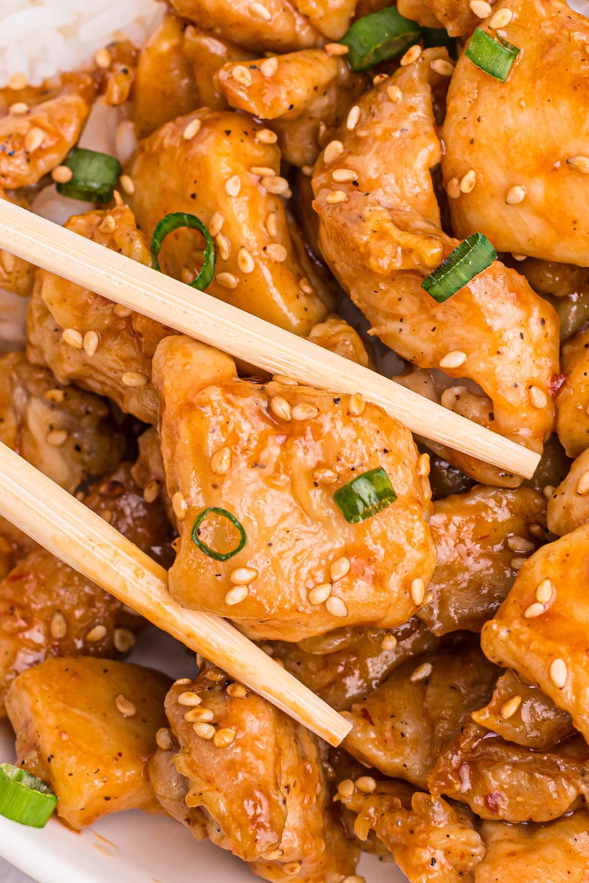air fried general tso's chicken with a pair of chopsticks
