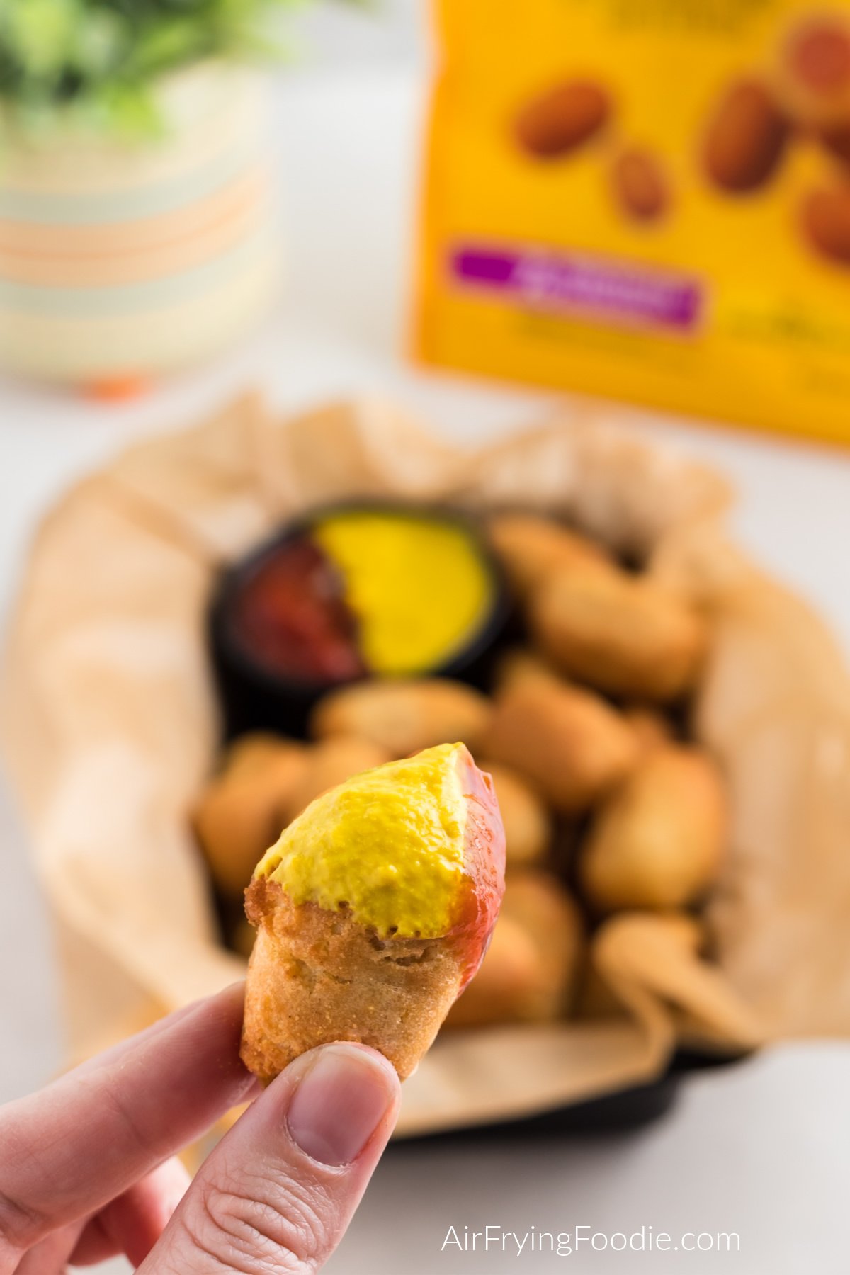Mini corn dog made in the air fryer, dipped in ketchup and mustard, ready to eat.