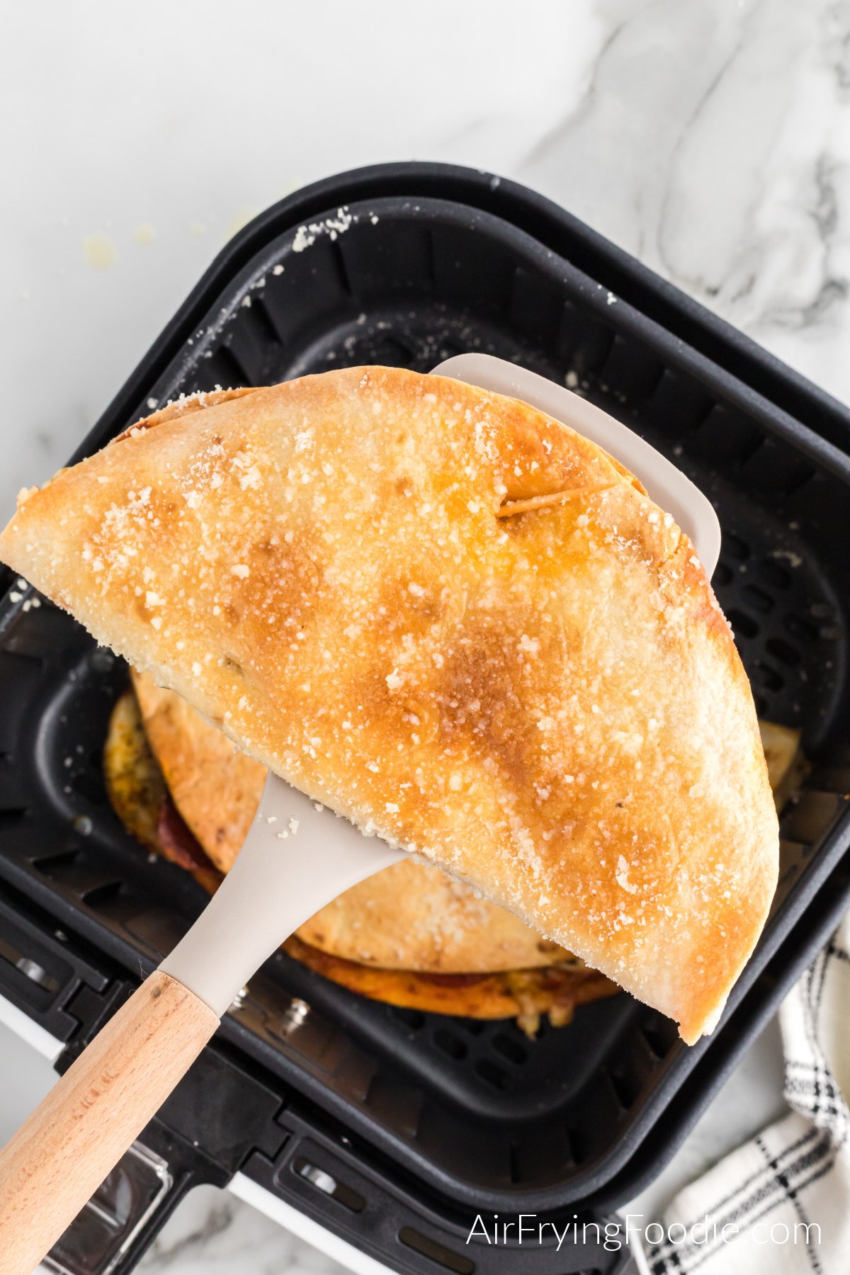 Pizza quesadilla on a spatula being removed from the air fryer.