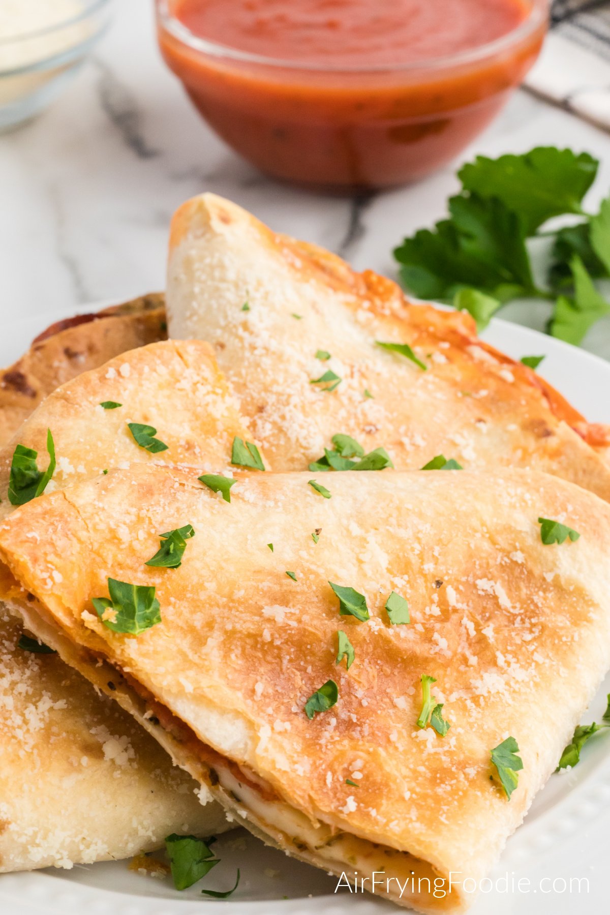 Pizza quesadilla made in the air fryer, topped with fresh parmesan cheese and parsley. 