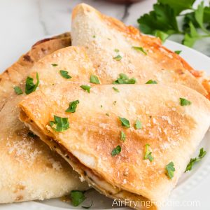 Pizza quesadilla made in the air fryer and topped with parmesan cheese and parsley.