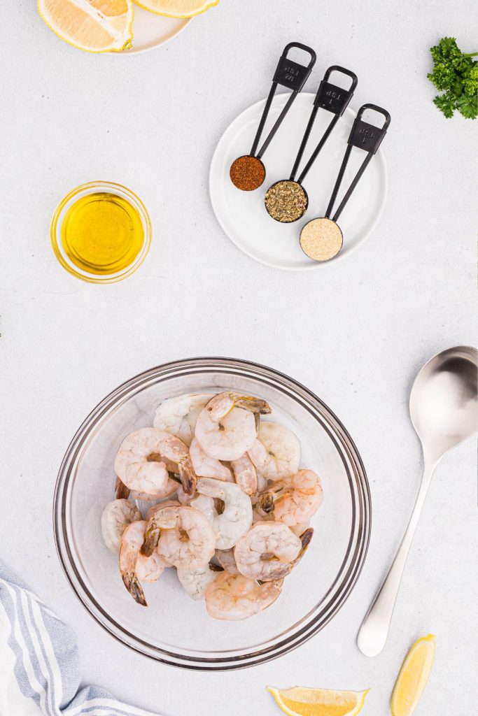 Ingredients needed to make seasoned shrimp measured out on a white marble table. 