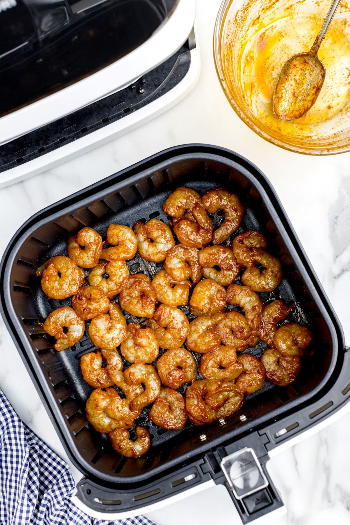 Seasoned shrimp in the air fryer basket before being cooked