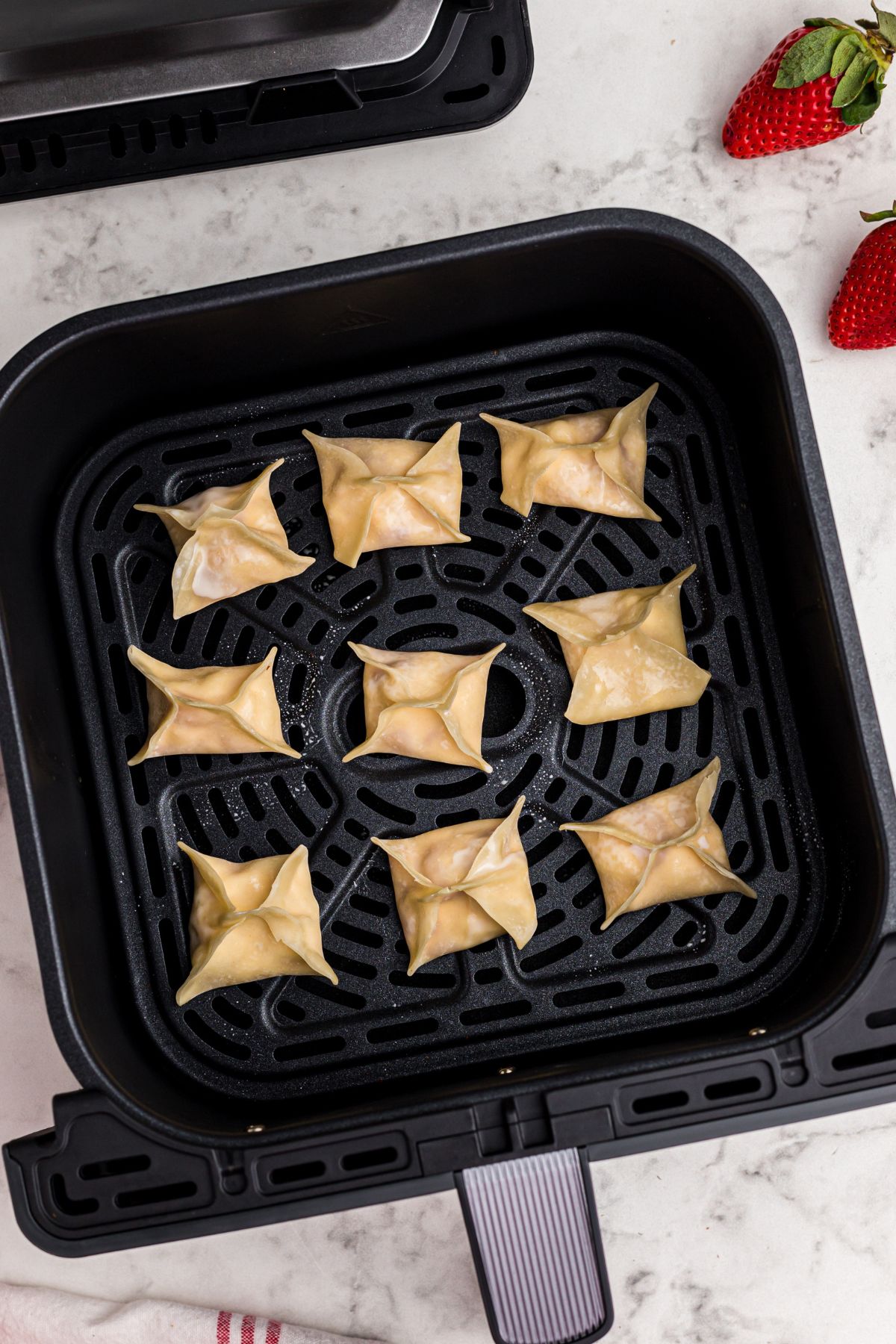 Uncooked stuffed wontons in the air fryer basket