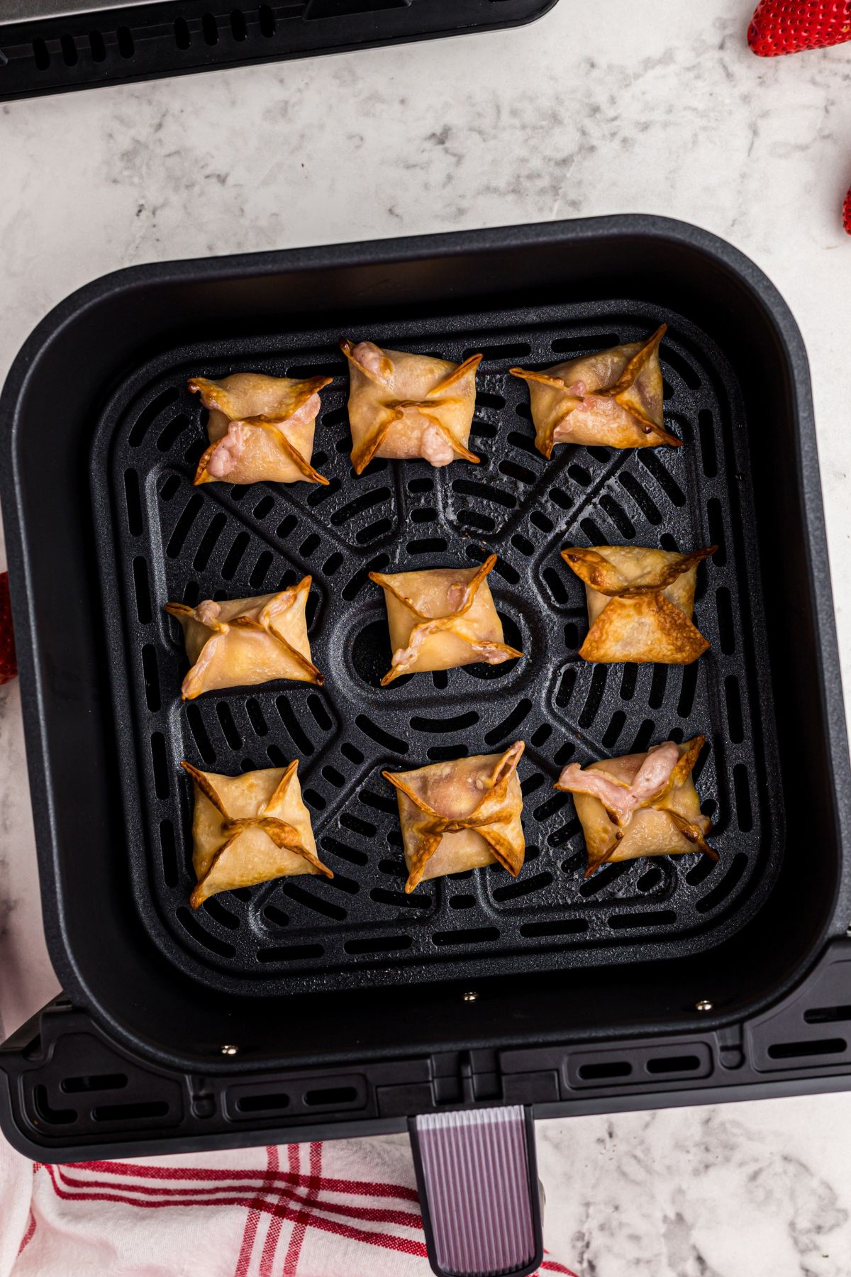Golden crispy cheesecake filled wontons in the air fryer basket.