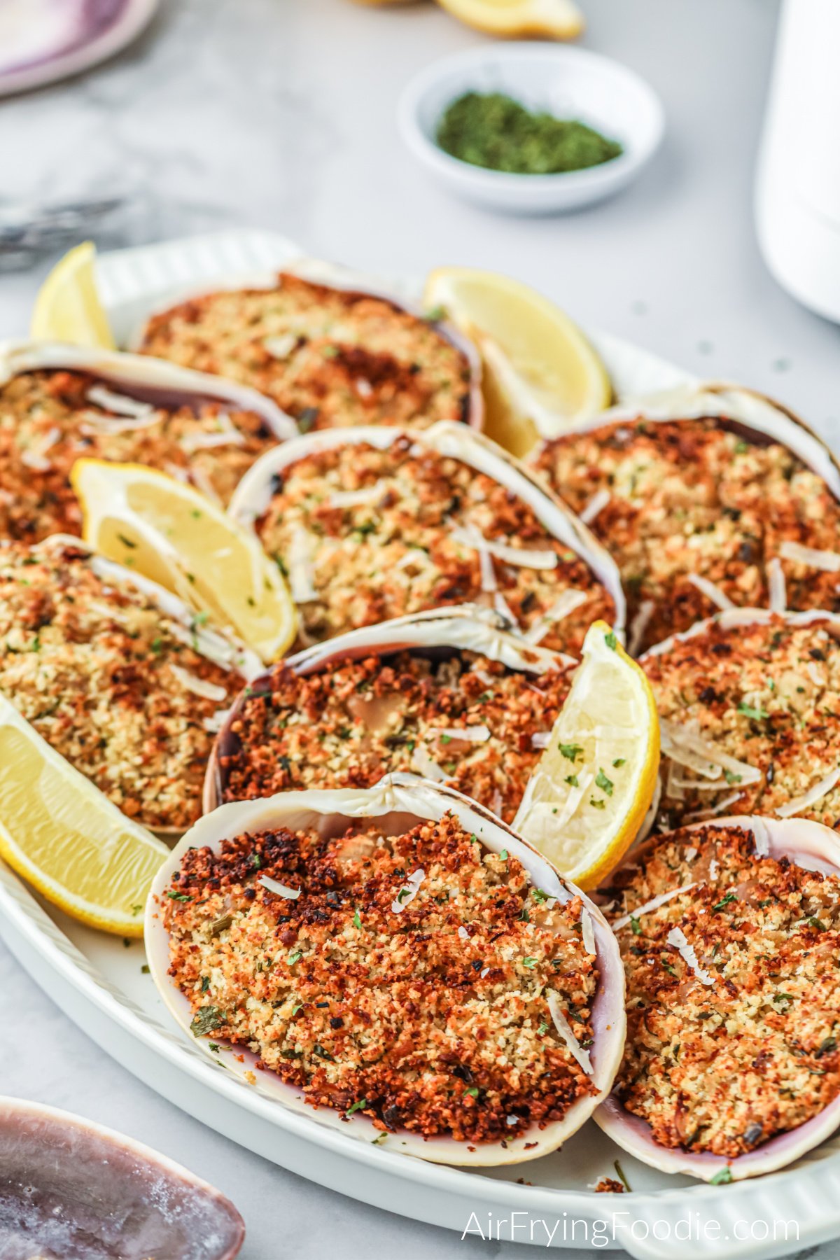 Air fried stuffed clams on a white plate with lemon wedges, ready to serve.