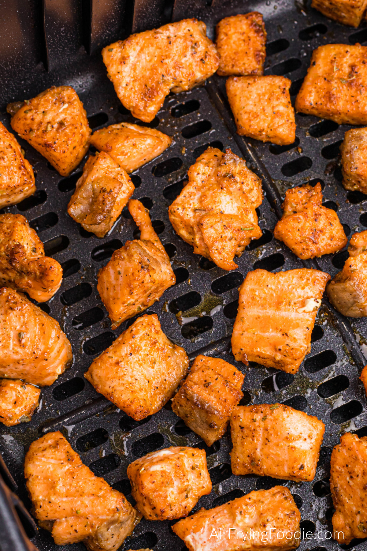 Blackened salmon bites in the basket of the air fryer.