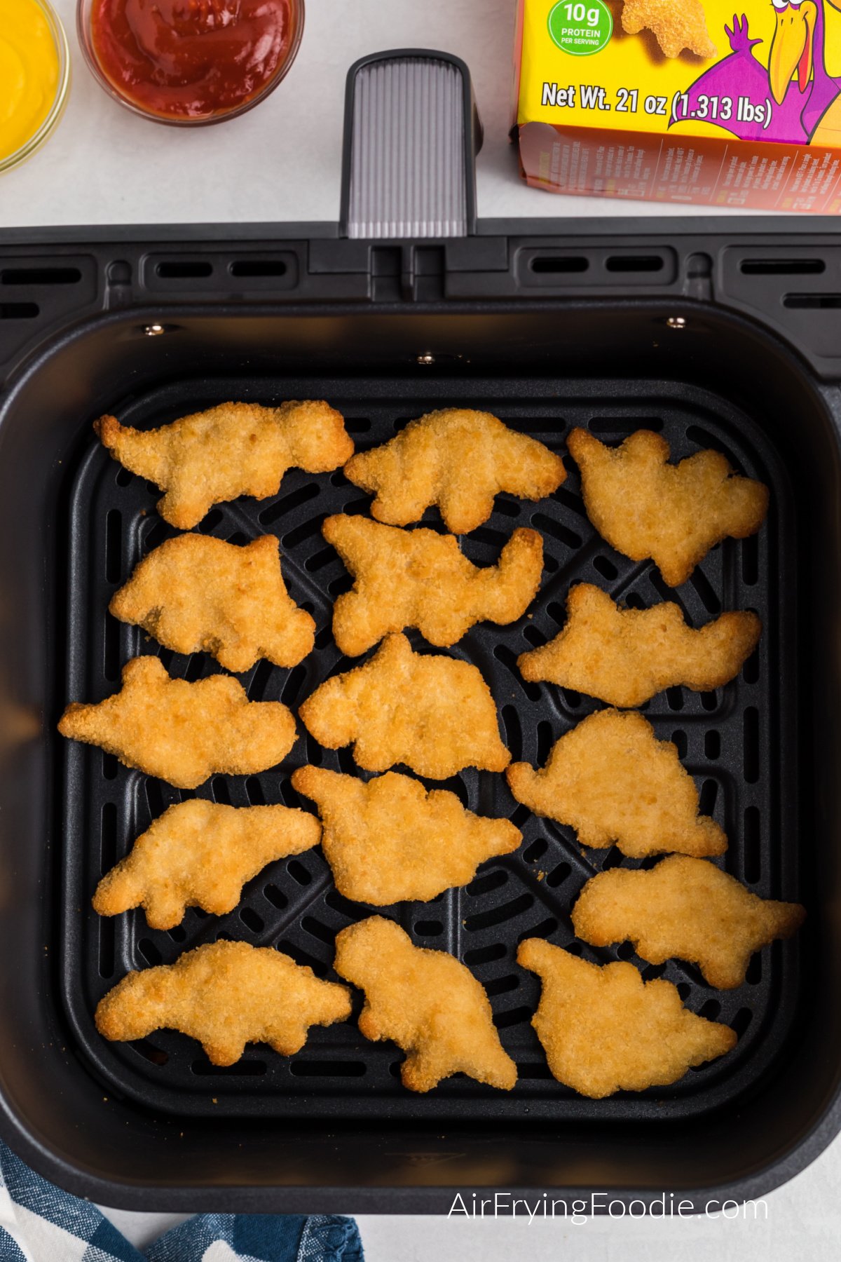 Single layer of air fried dino nuggets in the air fryer basket.