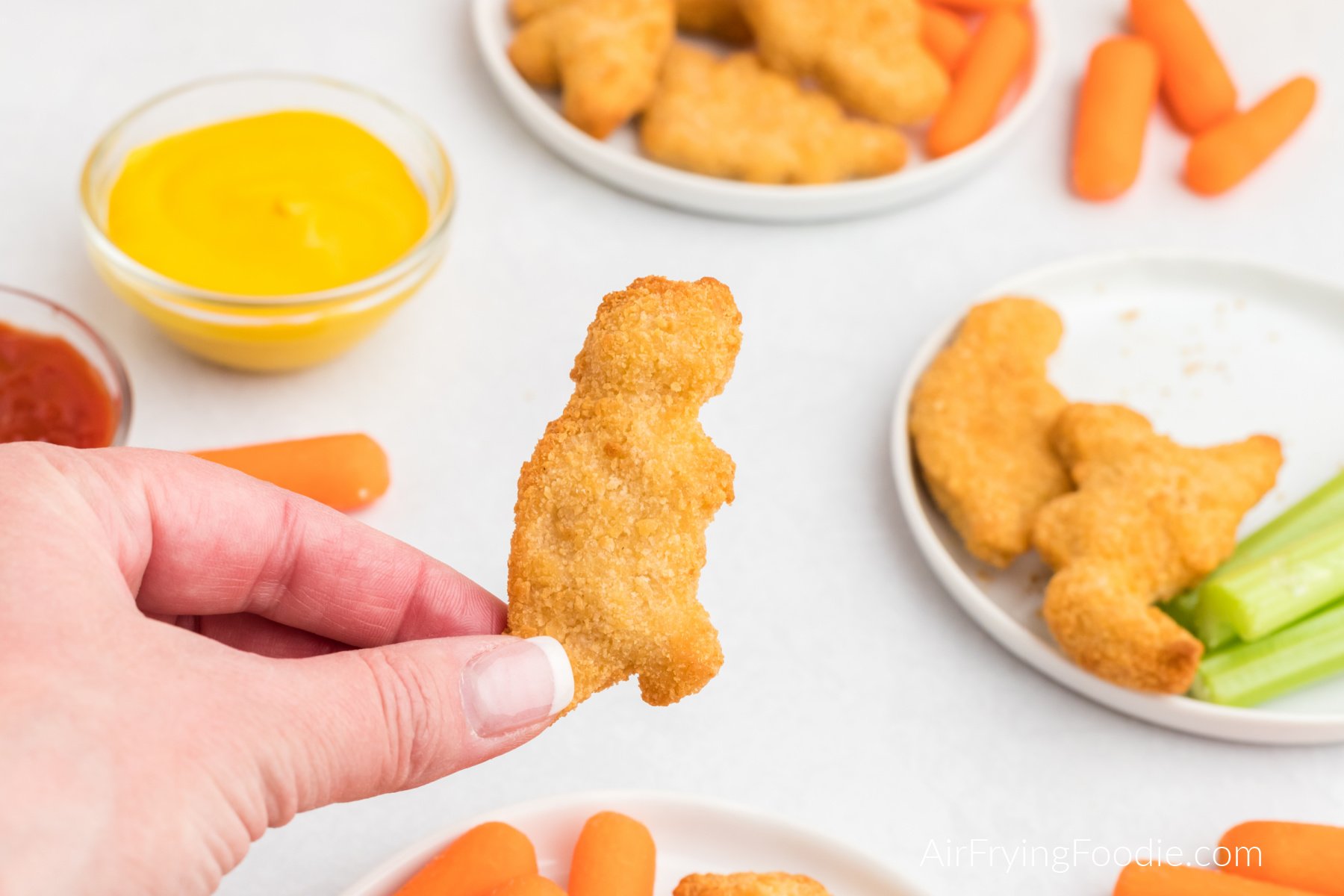 Hand holding a dino nugget made in the air fryer. 