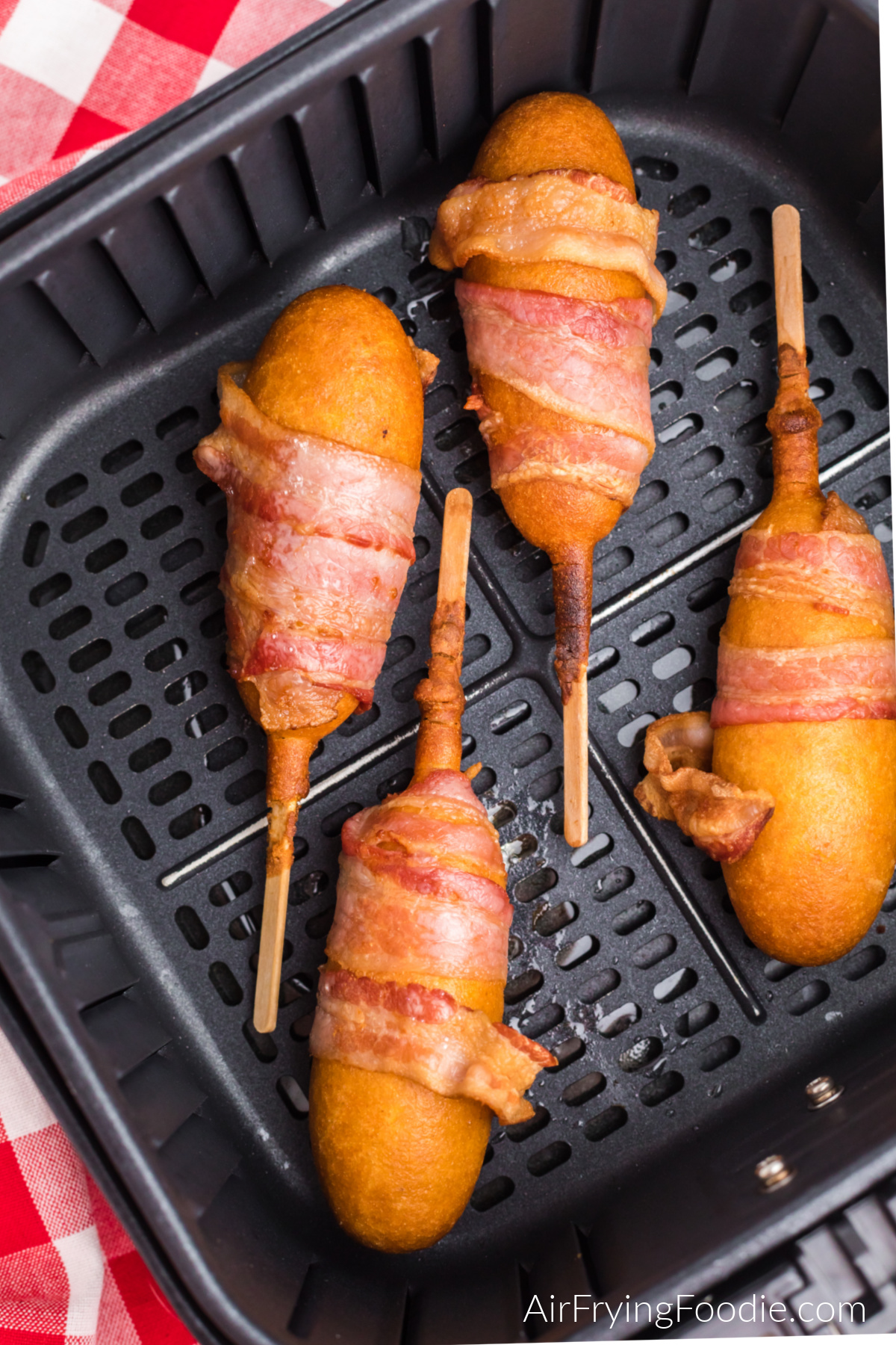 Bacon wrapped corn dogs in the air fryer basket, ready to serve.