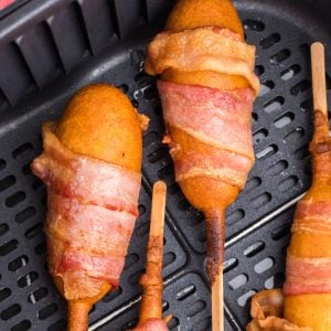 Bacon wrapped corn dogs in the air fryer basket, ready to serve.