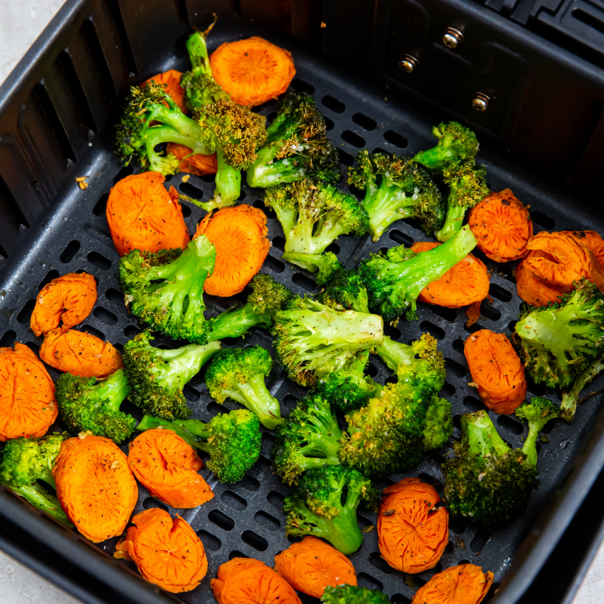Broccoli and carrots in the basket of the air fryer.