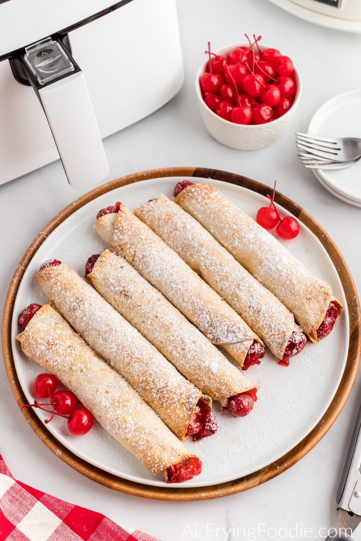 Air fryer cherry pie taquitos served on a plate and dusted with powdered sugar.