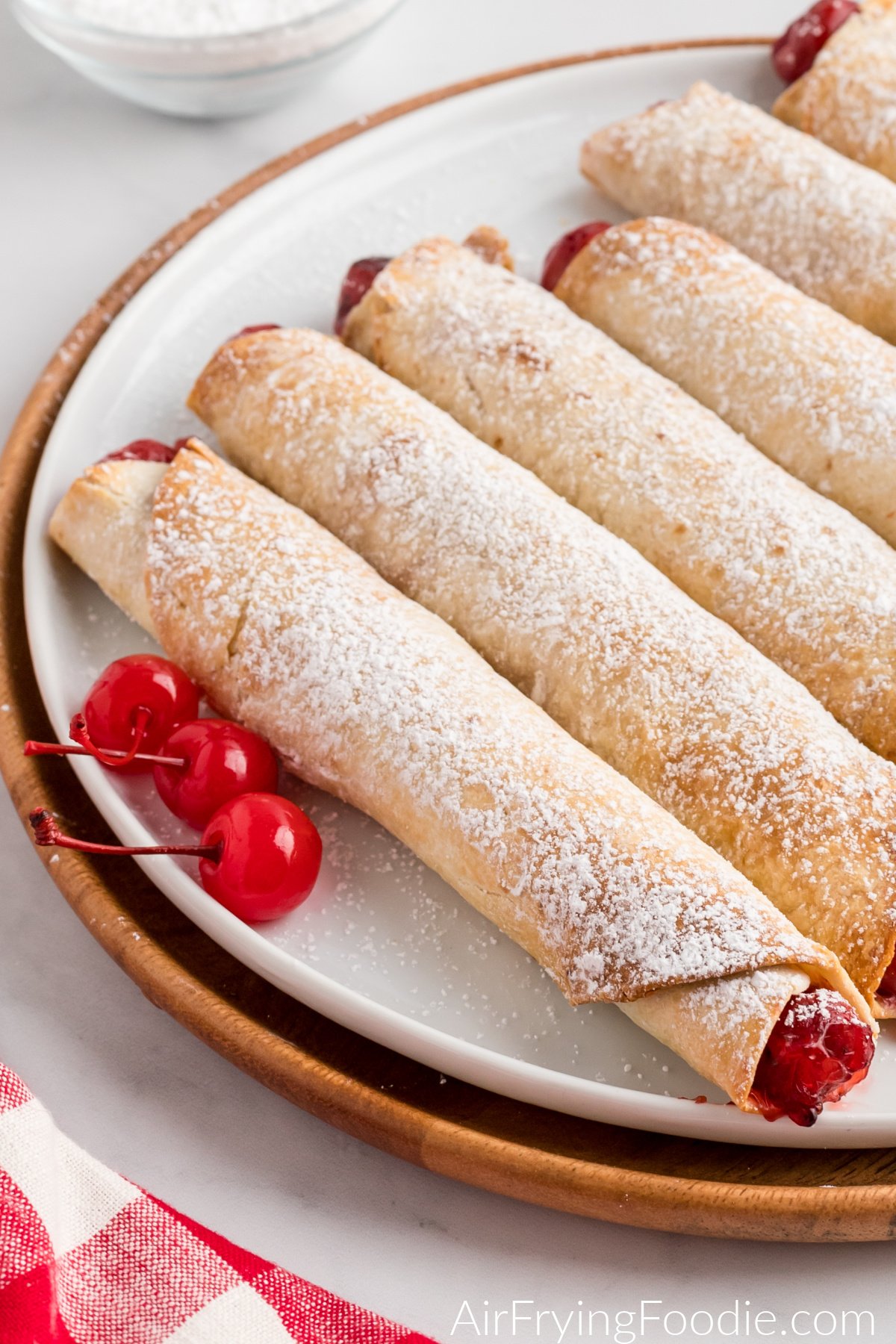 Cherry pie taquitos on a plate and dusted with sugar. 
