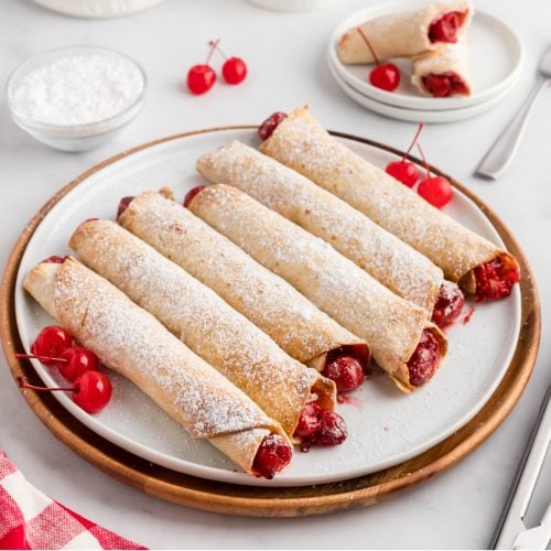 Cherry Pie Taquitos made in the air fryer on a plate with powdered sugar dusted on top.