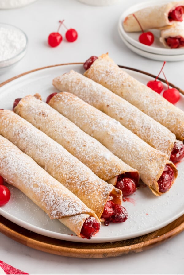 Cherry Pie Taquitos made in the air fryer on a plate with powdered sugar dusted on top.