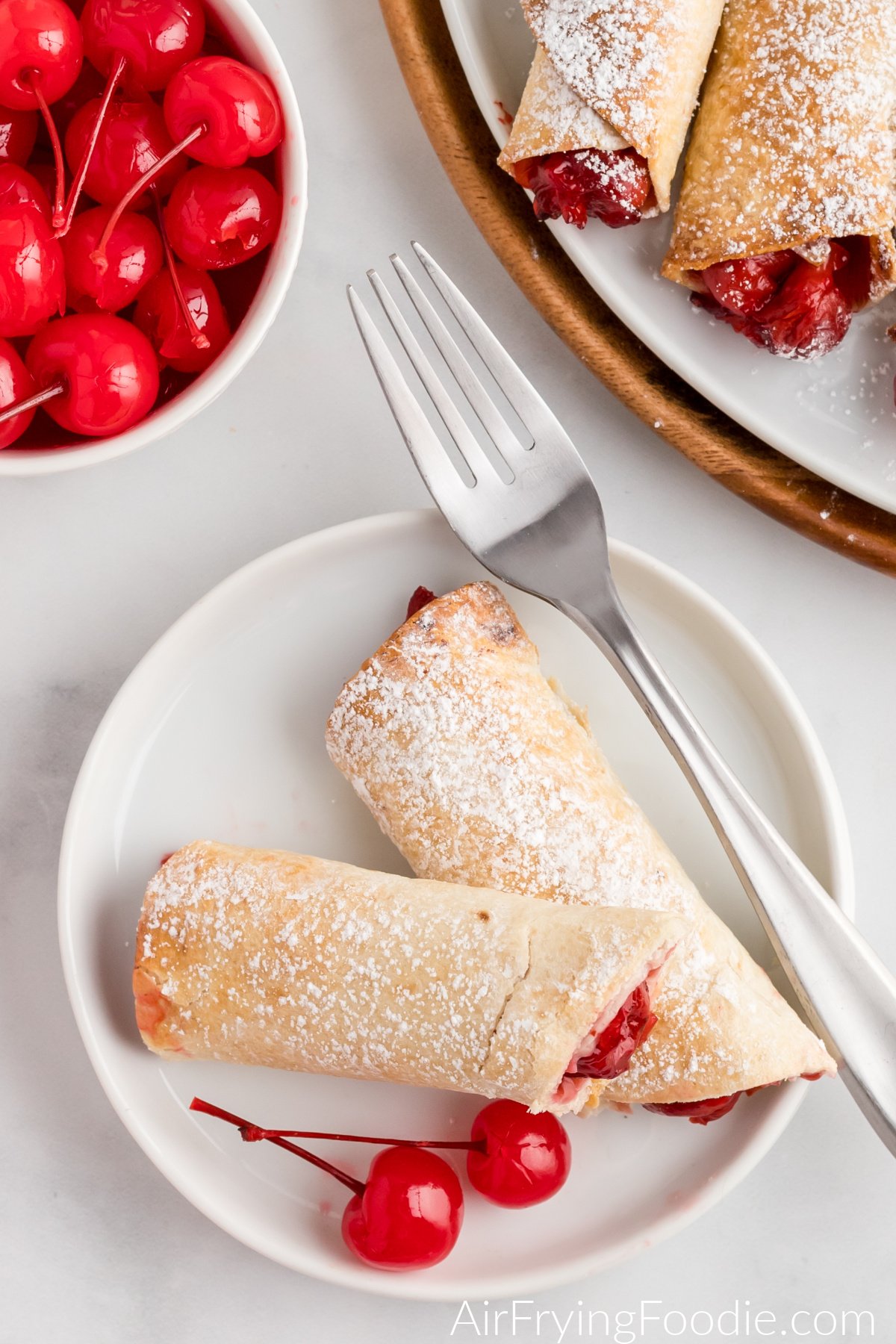 Air fried cherry pie taquitos on a white plate ready to eat.
