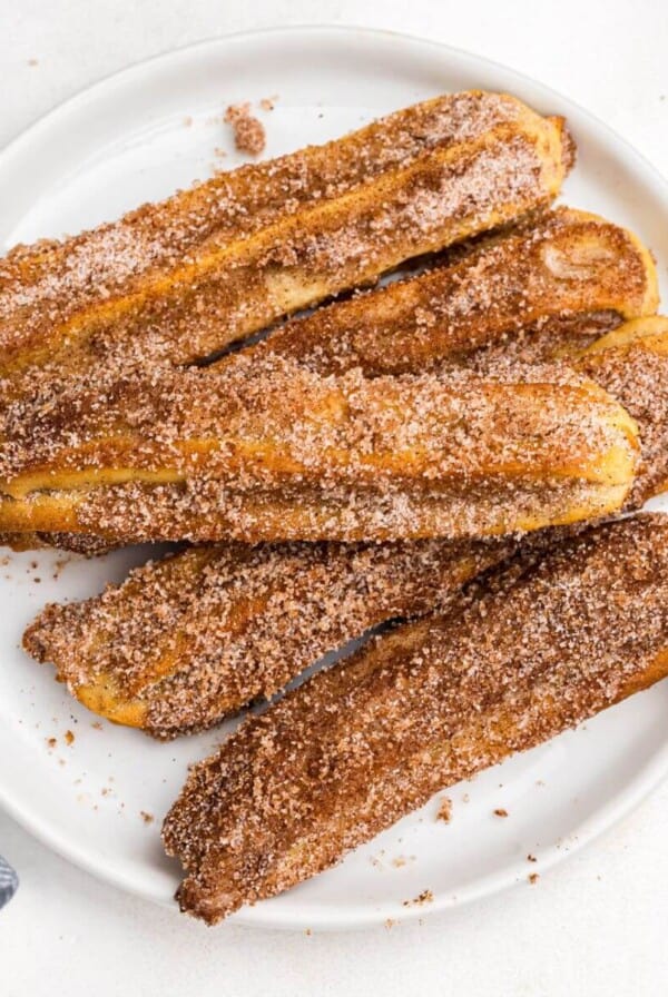 Cinnamon and sugar coated churros on a white plate