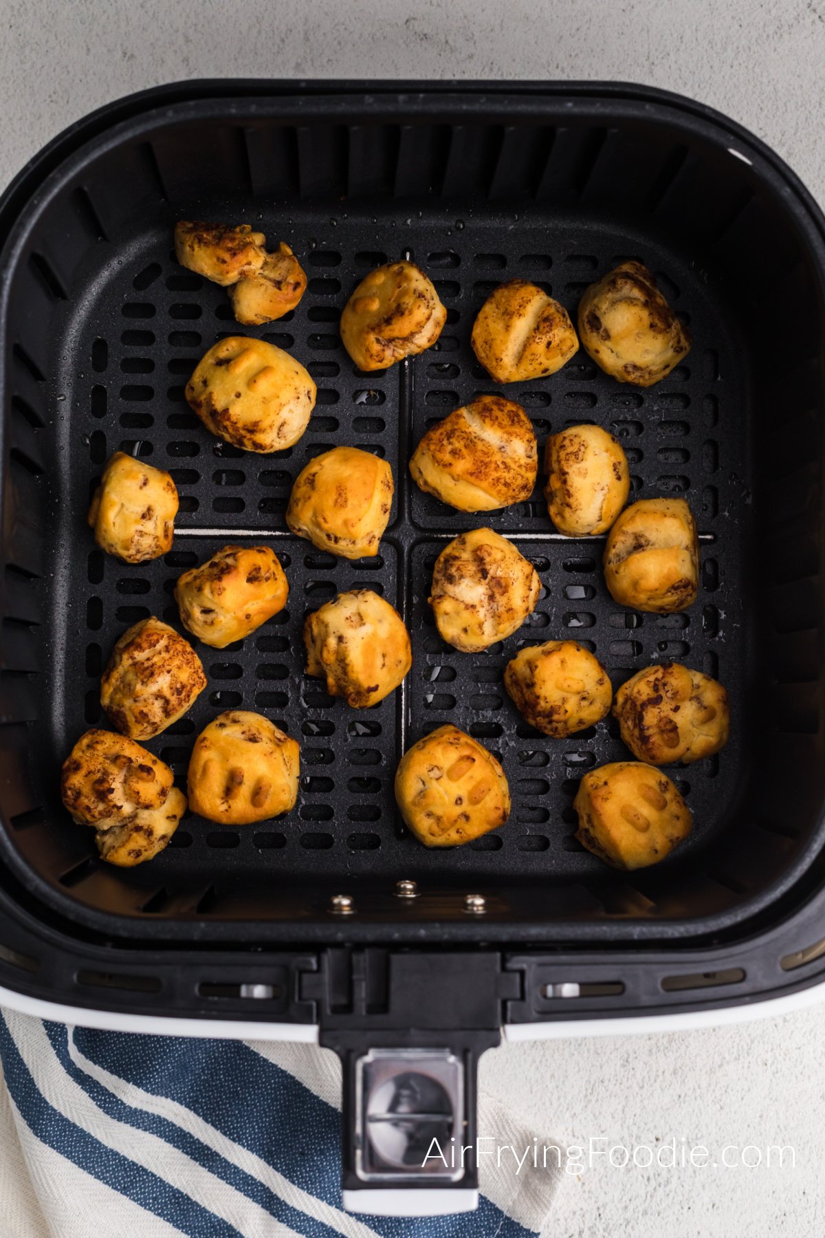 Cinnamon roll balls air fried to a golden brown in the basket of the air fryer.