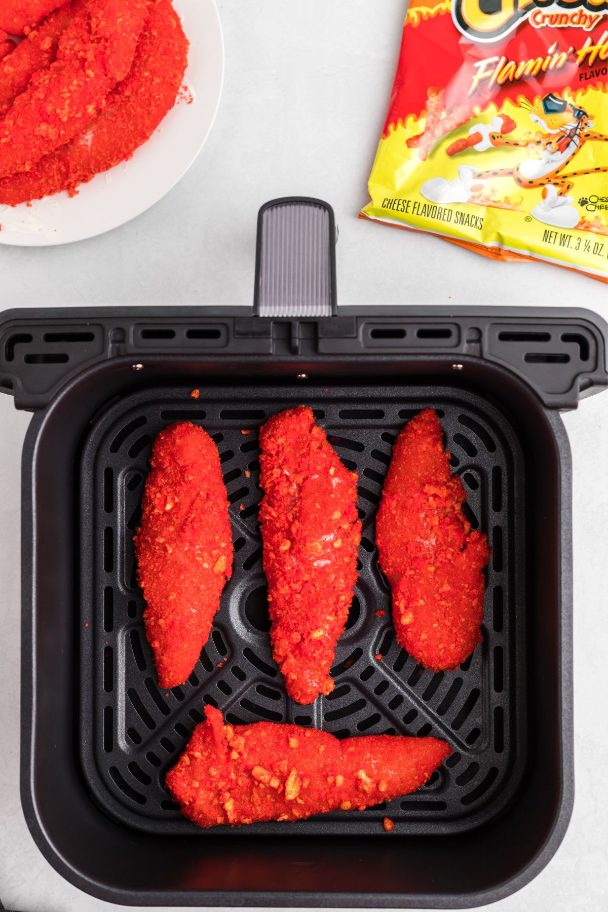 Coated cheeto chicken in the air fryer basket before being cooked