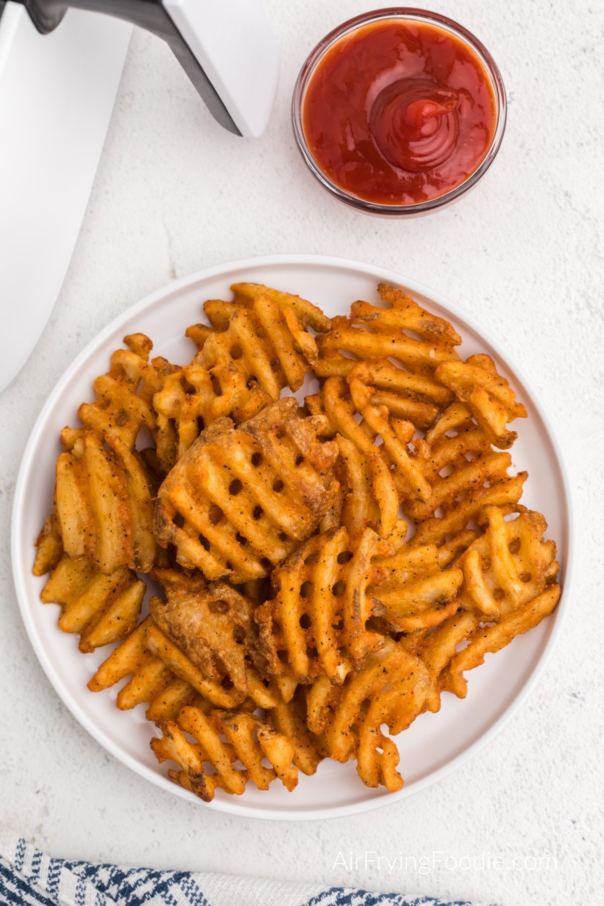 Air fried waffle cut fries on a white plate, ready to eat. 