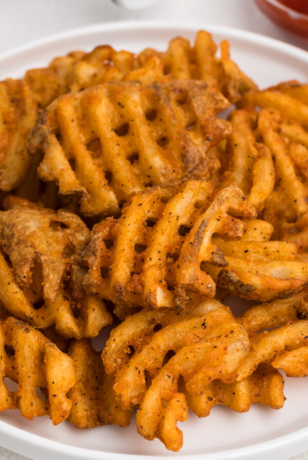 Waffle fries made in the air fryer, served on a white plate.