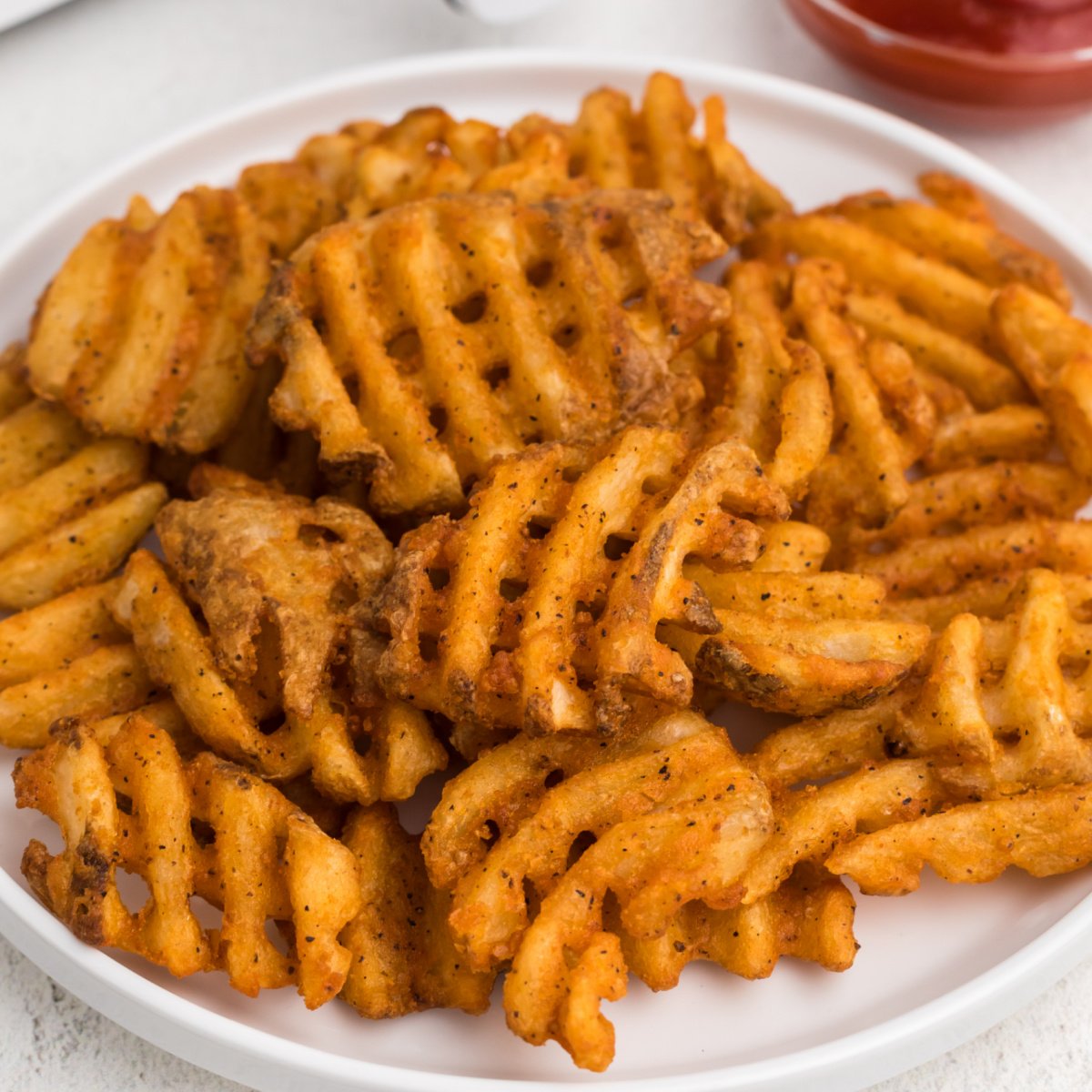 Waffle fries made in the air fryer, served on a white plate.