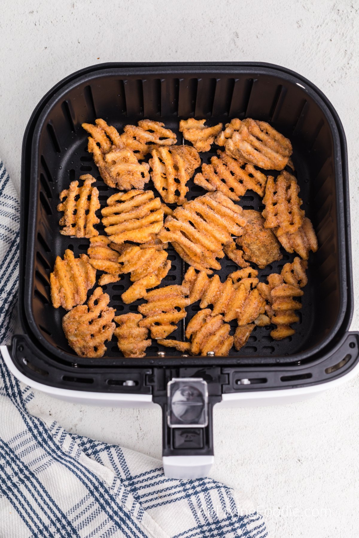 frozen waffle fries in the basket of the air fryer.