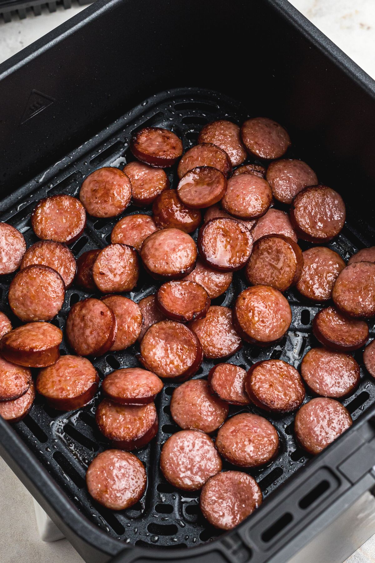 Easy Air Fryer Kielbasa 6 Juicy, perfectly cooked kielbasa slices in the air fryer basket, ready to be served.
