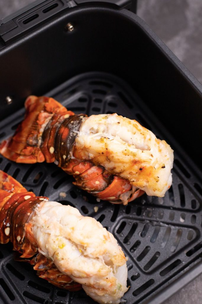Juicy cooked lobster tails in the air fryer basket. 