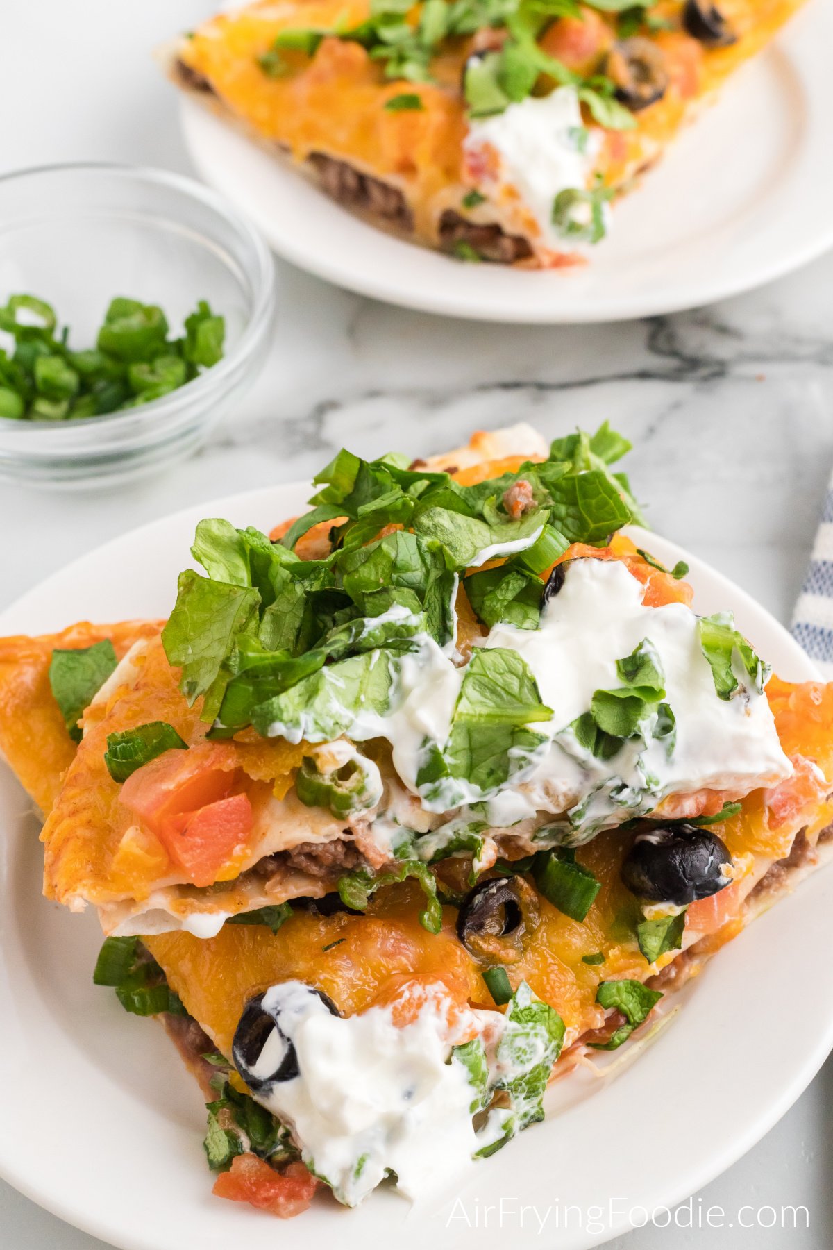 Sliced mexican pizza topped with lettuce and sour cream and ready to eat.