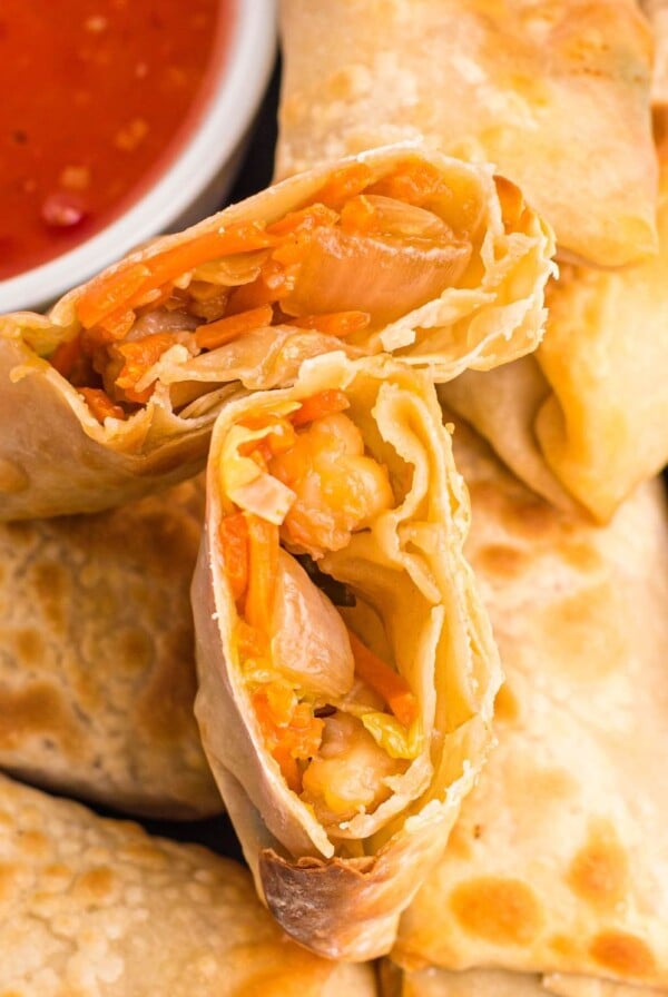 Golden crispy egg rolls on a plate with dipping sauce