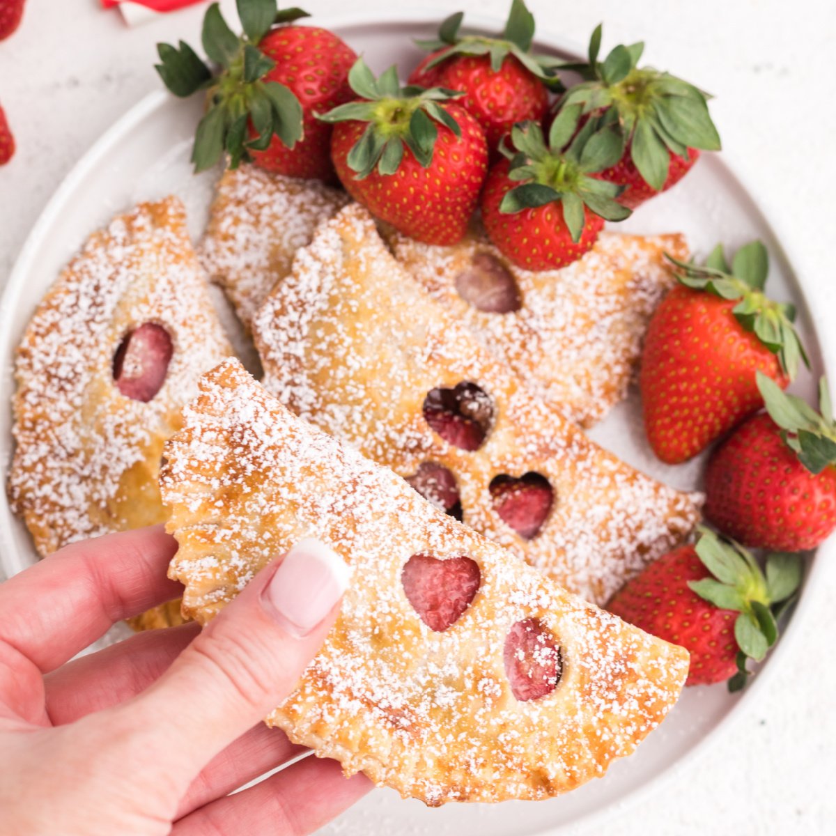 Strawberry nutella hand pies made in the air fryer and ready to eat. One being held.