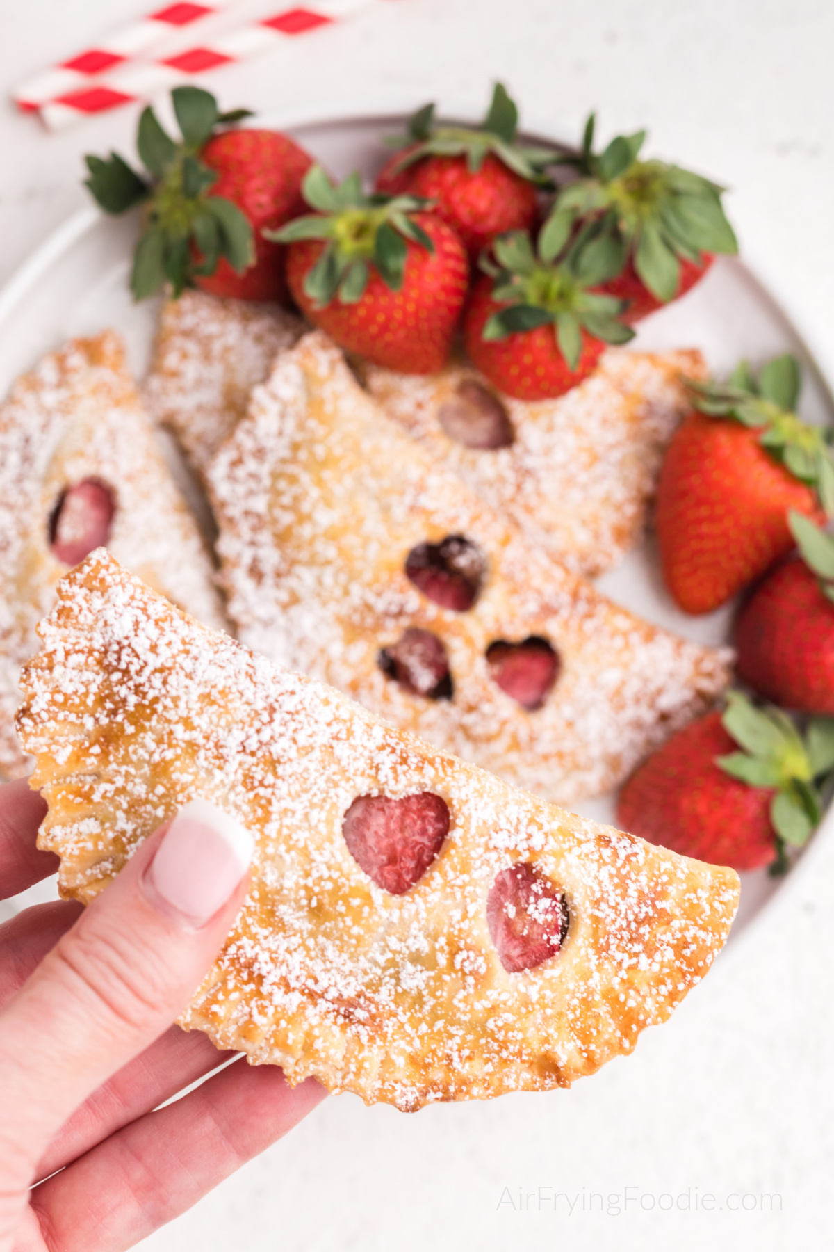 Hand holding a strawberry nutella hand pie dusted with powdered sugar.