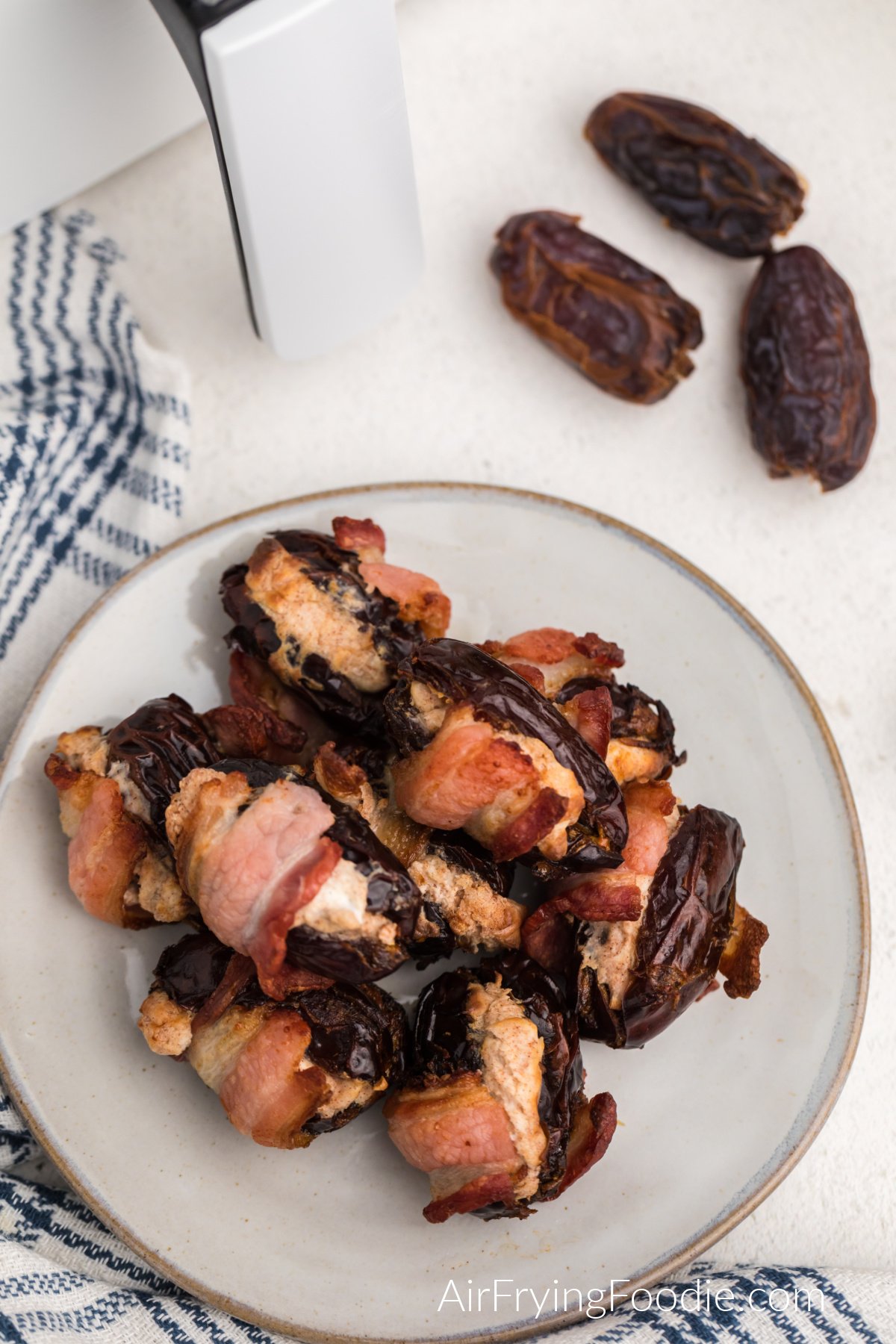 Overhead photo of cream cheesed stuffed bacon wrapped dates on a plate.