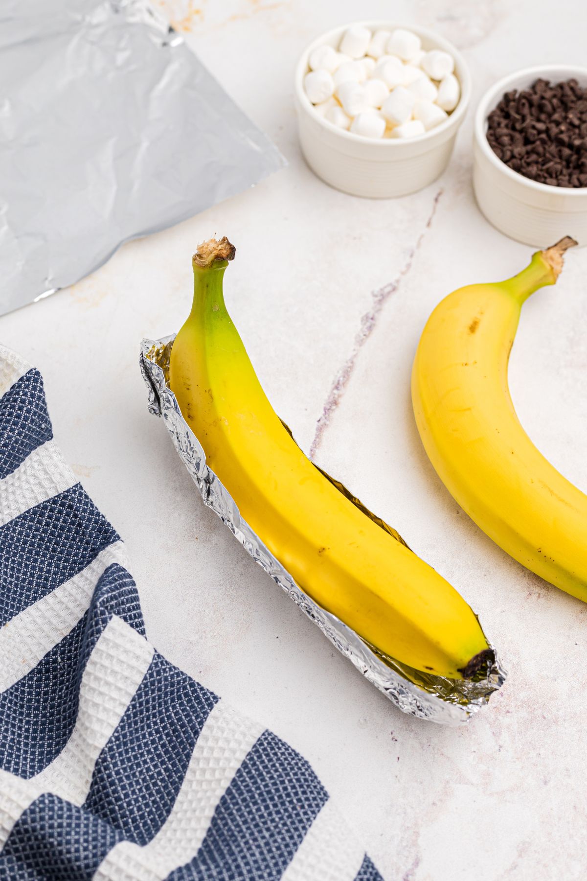 Bananas sitting in foil sling on a marble table.