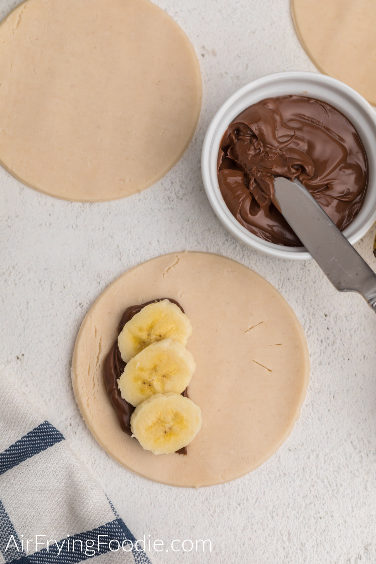 Sliced bananas on top of nutella on a pie crust.